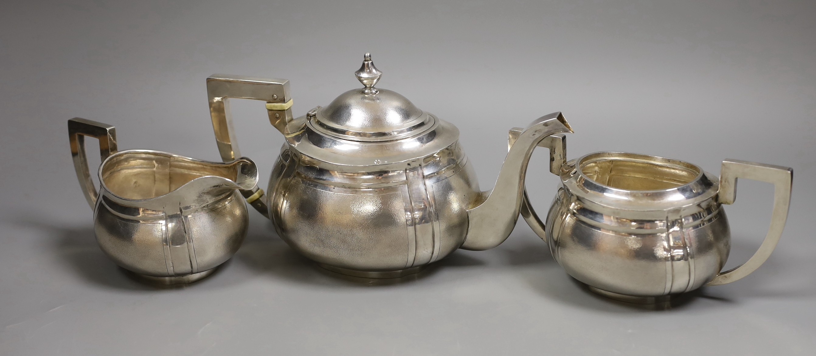 An early 20th century Chinese Export white metal three piece tea set, by Hung Chong?, with bone insulators, gross weight 33oz.